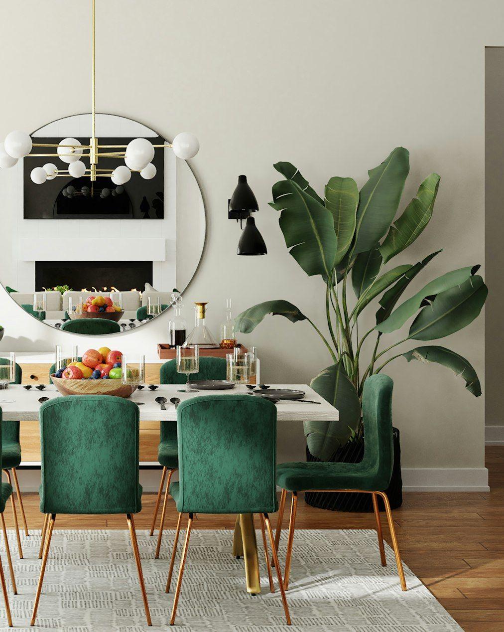 Dining room with green velvet chairs and round mirror