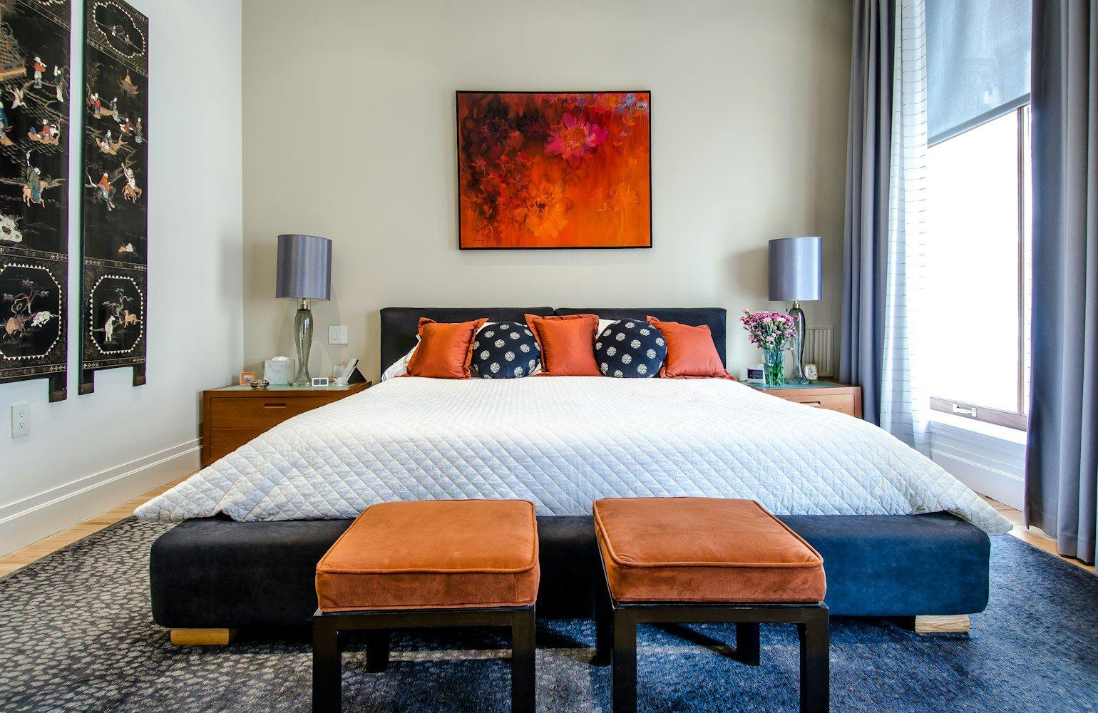 Bedroom with upholstered headboard and orange ottomans