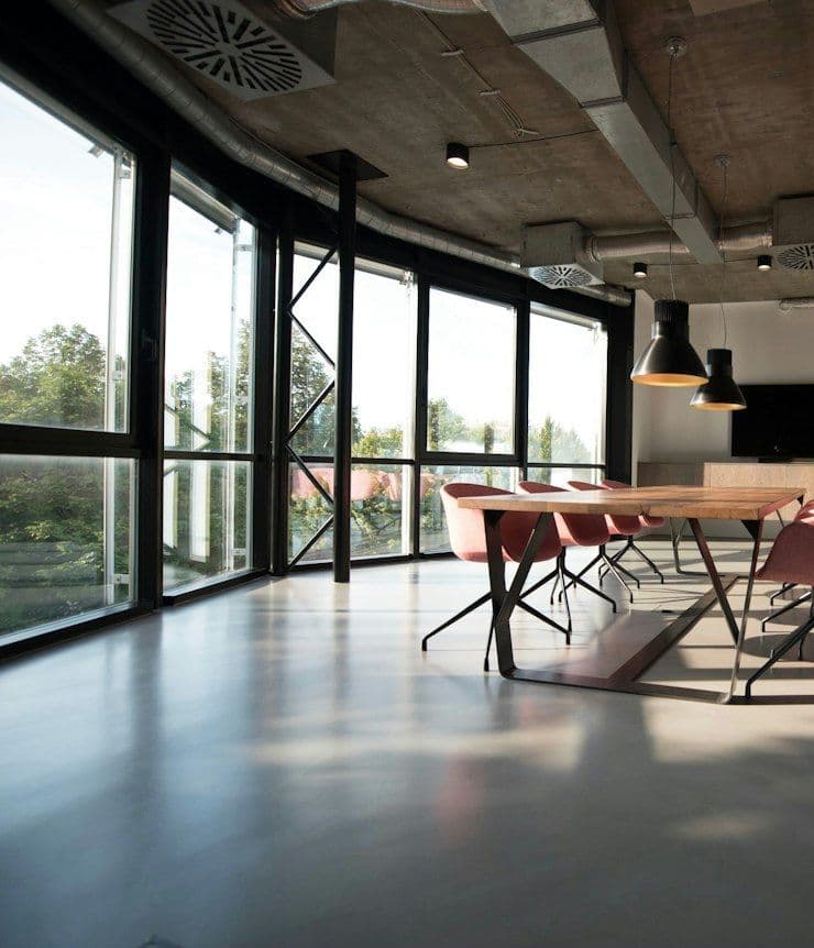 Open office with long timber tables and black pendant lights